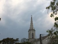 Foto colorida da torre da Igreja Matriz de São Luiz Gonzaga com o céu carregado de nuvens