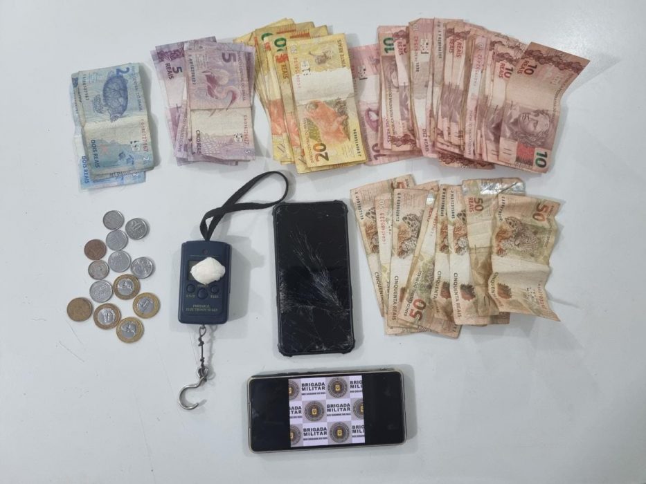 foto colorida de dinheiro, celular e drogas apreendidas em mesa branca