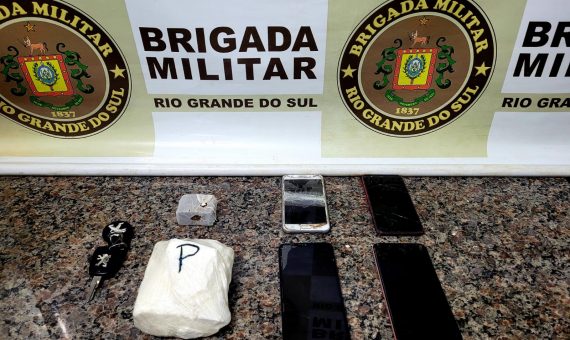 foto colorida de drogas apreendidas em Bossoroca em cima de uma mesa com banner da Brigada Militar ao fundo