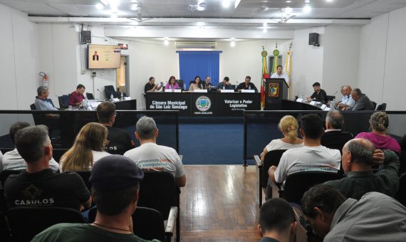 Foto colorida da Câmara Municipal de Vereadores de São Luiz Gonzaga vista de fundo com pessoas assistindo a sessão e vereadores na bancada